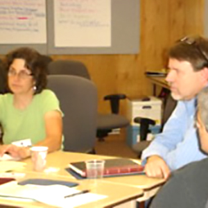 Three people sitting around a table and listening.