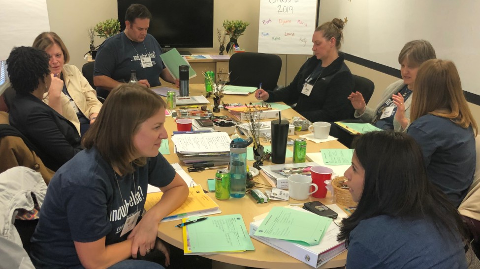 Group of people talking and sitting around a round table.