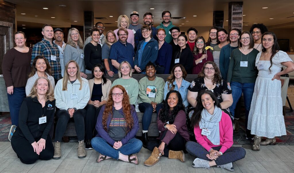 Group of people four rows deep smiling.